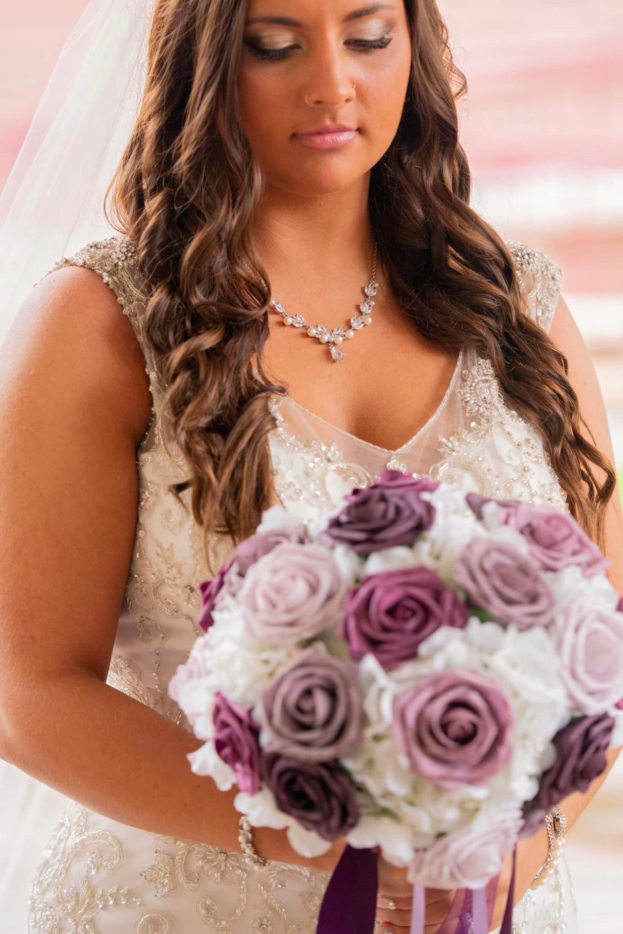Bride holding an elegant purple and white rose artificial bouquet, demonstrating Forever Flowers by Val's sophisticated floral design